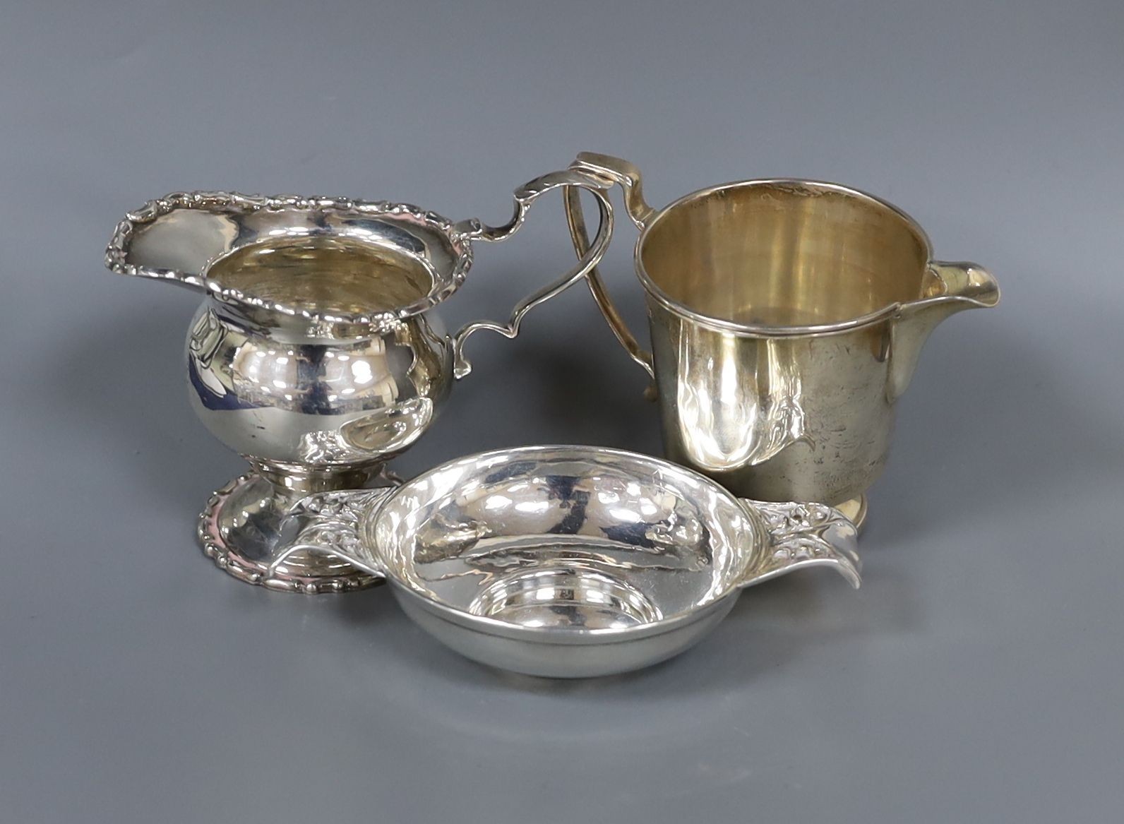 A late Victorian Art Nouveau small silver two handled dish, by W.G Connell, London, 1900, 12cm and two silver cream jugs, 7oz